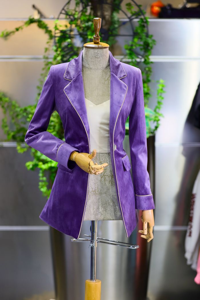 why-choose-us Elegant purple velvet jacket displayed on a mannequin in a stylish boutique setting.