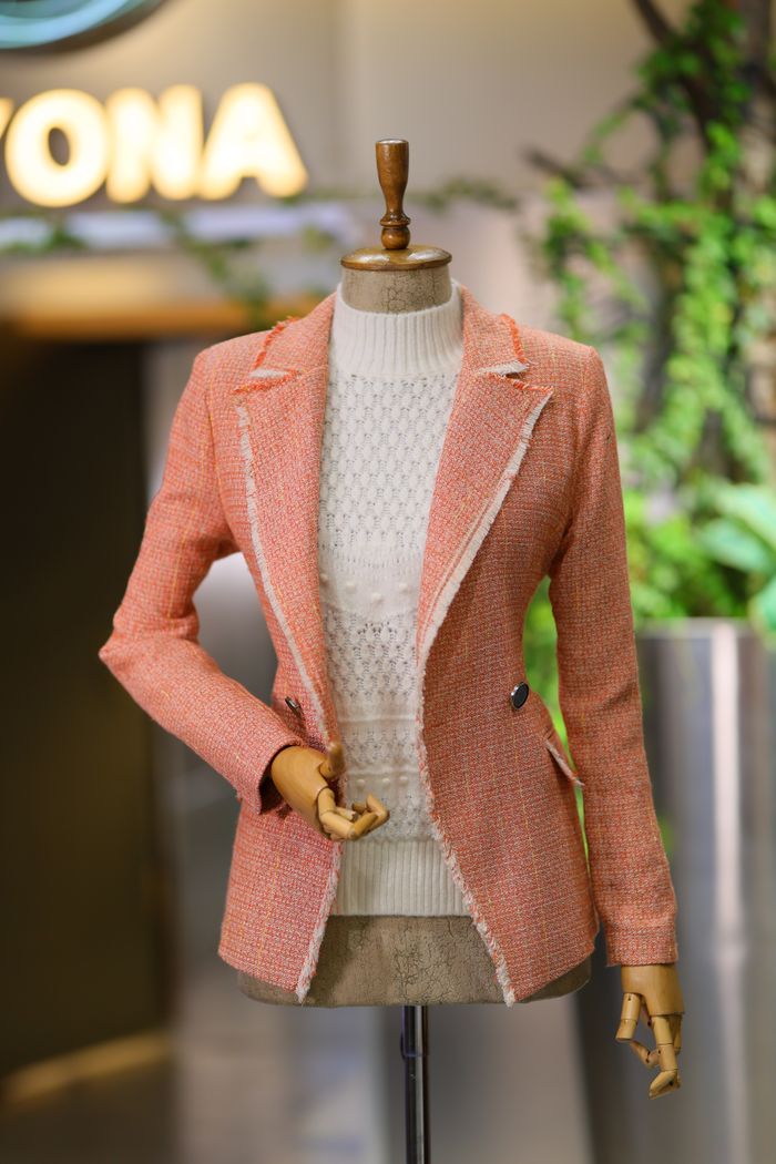 team-02 Stylish pink blazer displayed on mannequin in a modern boutique with vibrant decor.