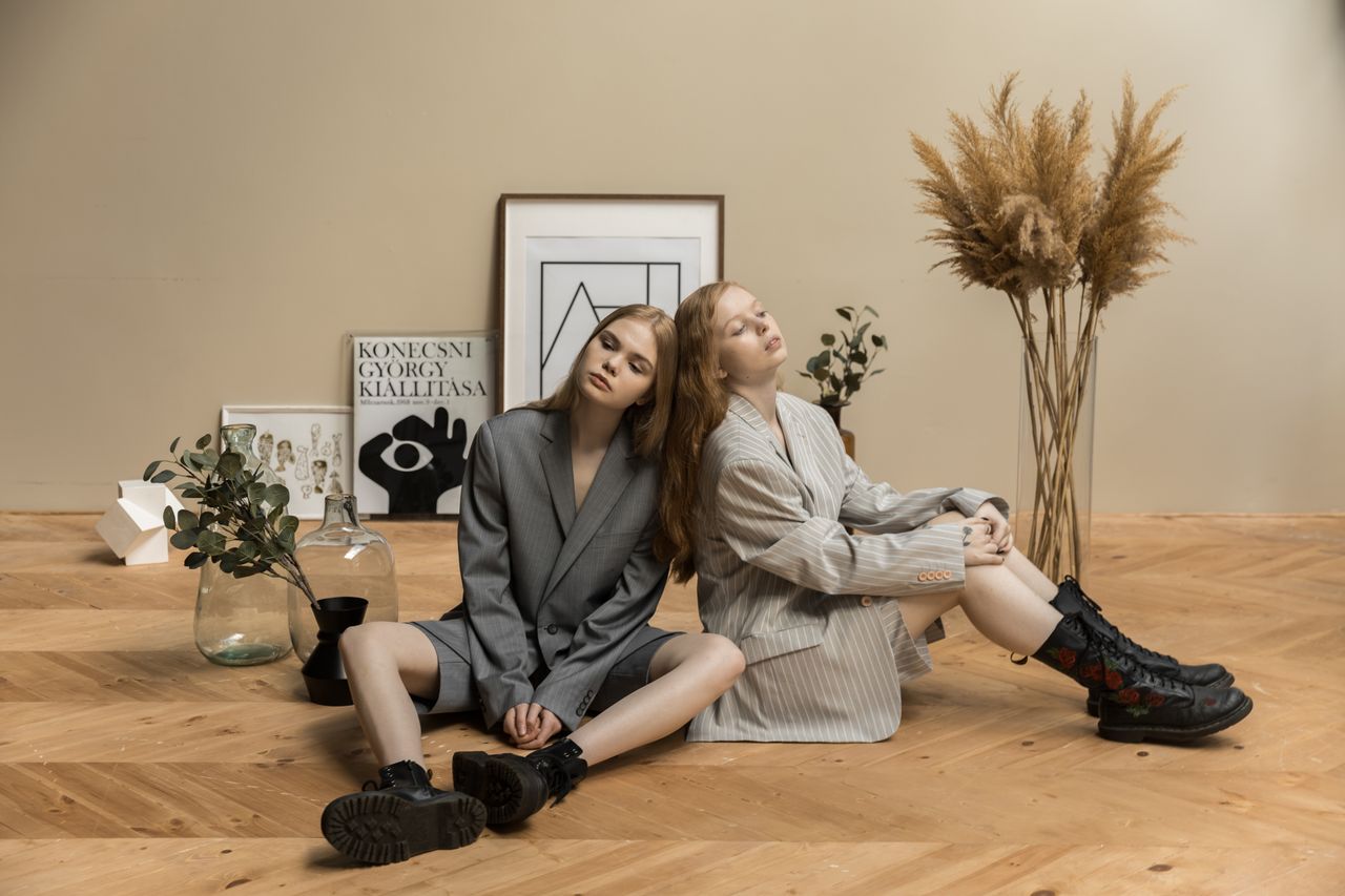 team-04 Two women in suits pose artistically indoors with a minimalist style.