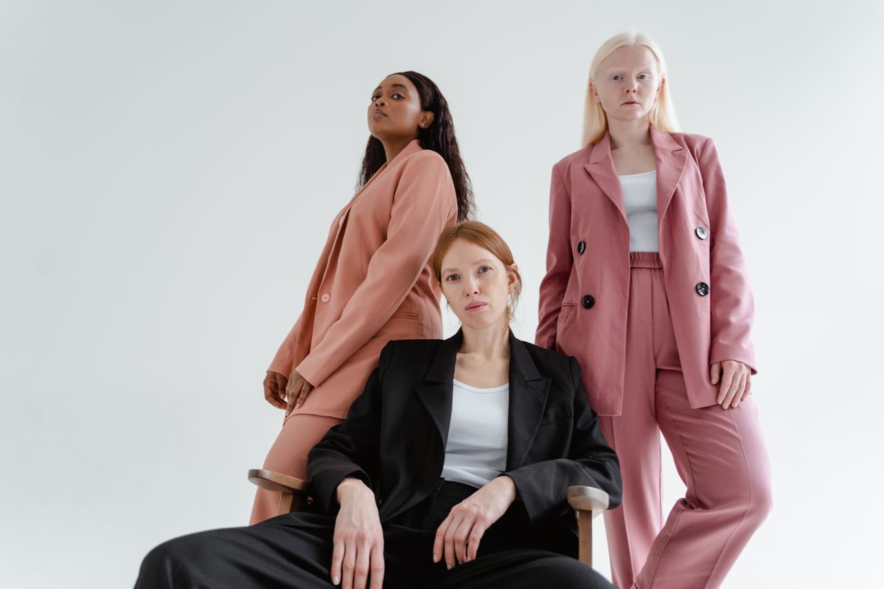 services-01 Three diverse women posing confidently in stylish blazers in a white studio setting.